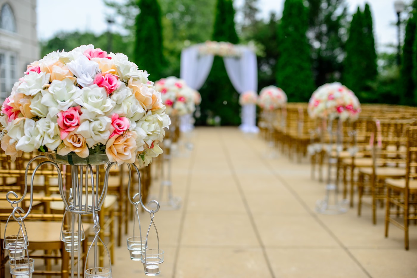 Festlich geschmückter Zeremonienweg mit Blumengestecken aus Rosen in Weiß und Rosé