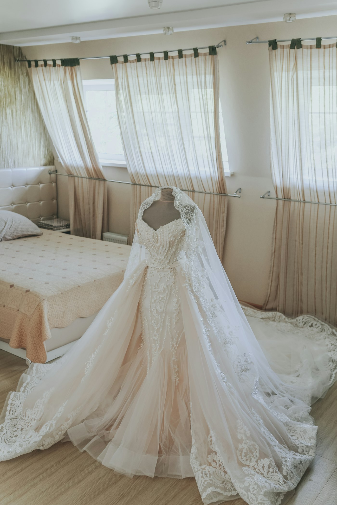 Brautkleid mit Perlenstickerei und langer Spitzenschleppe auf einer Schneiderbüste