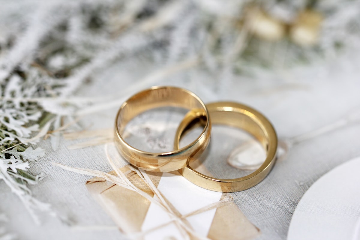 Zwei goldene Trauringe auf festlich dekoriertem Stoff